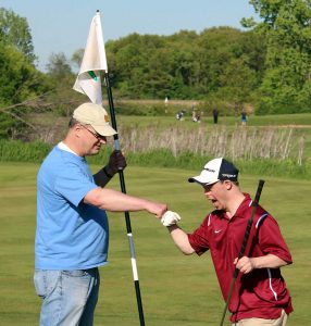 Volunteer Fist-Bumping Golf Participant